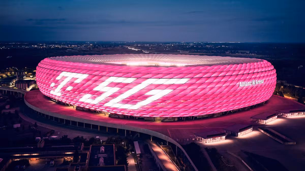 Allianz Arena bei Nacht in Pink mit großem Telekom-Logo auf der Fassade.